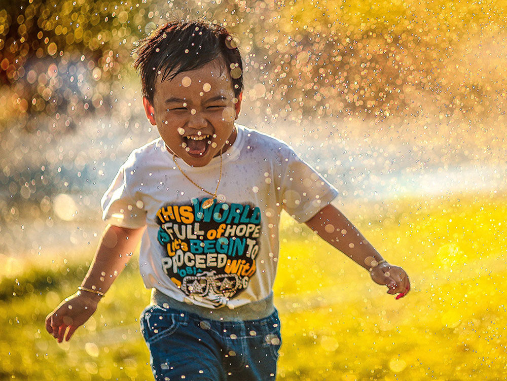 Boy playing in sprinklers